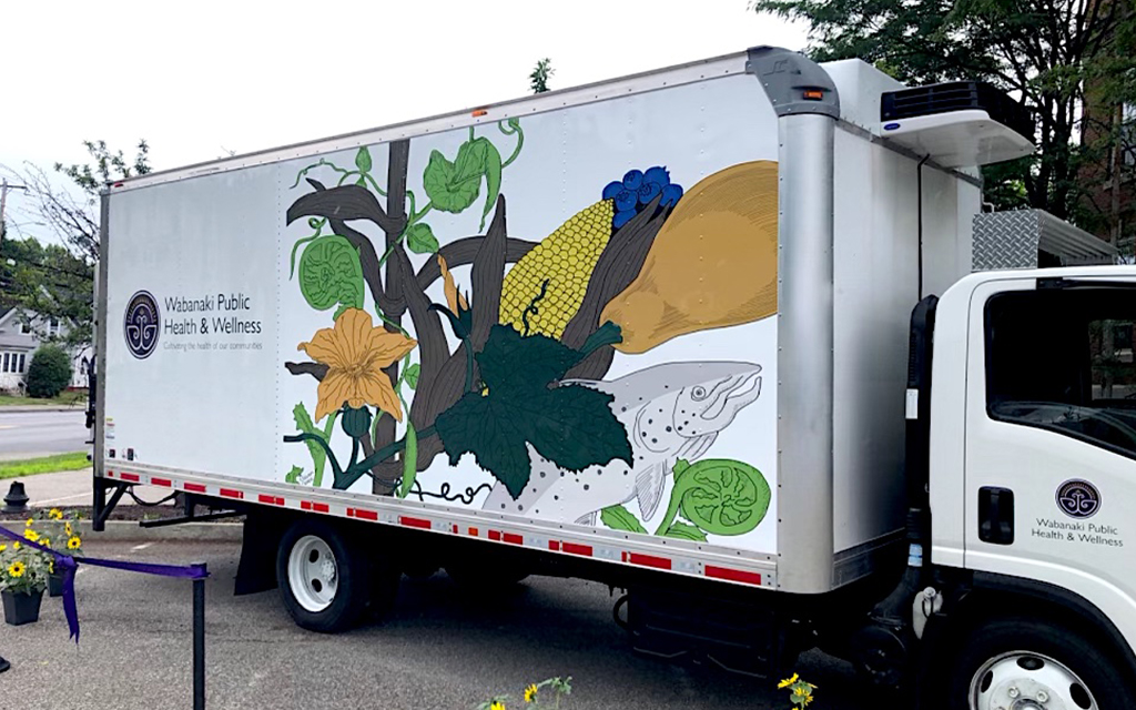 WPHW's mobile food pantry is displayed: a truck with images of corn, squash, fiddleheads, fish, and beans is on the side.